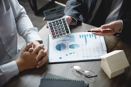 Two people reviewing a calculator and documents showing graphs