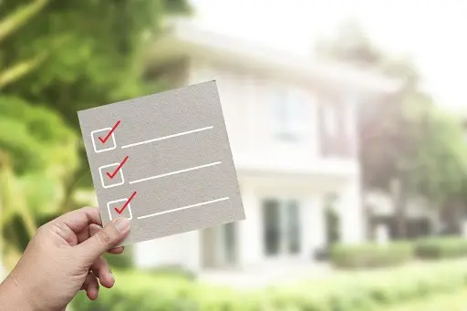 A checklist in the foreground with a house out of focus in the back