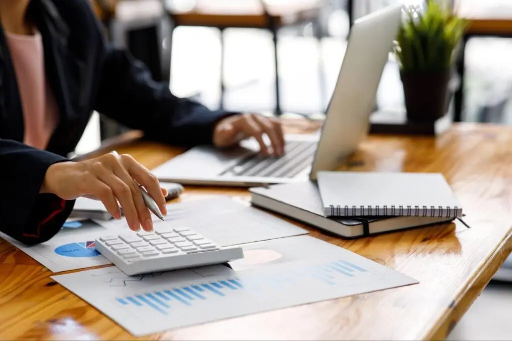 Image of a businesswoman calculating and using her laptop.
