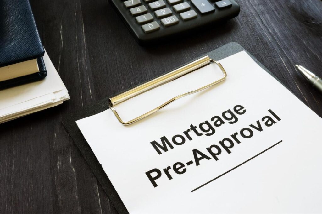 A clipboard on a desk holds a white piece of paper with the words “Mortgage Pre-Approval” on it.