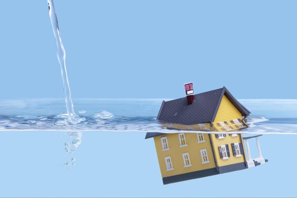 A yellow home sinks underwater as more water continues to pour in.