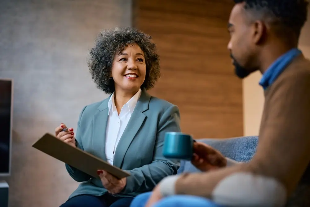 Female lender speaking to African-American man about refinancing for home improvements.