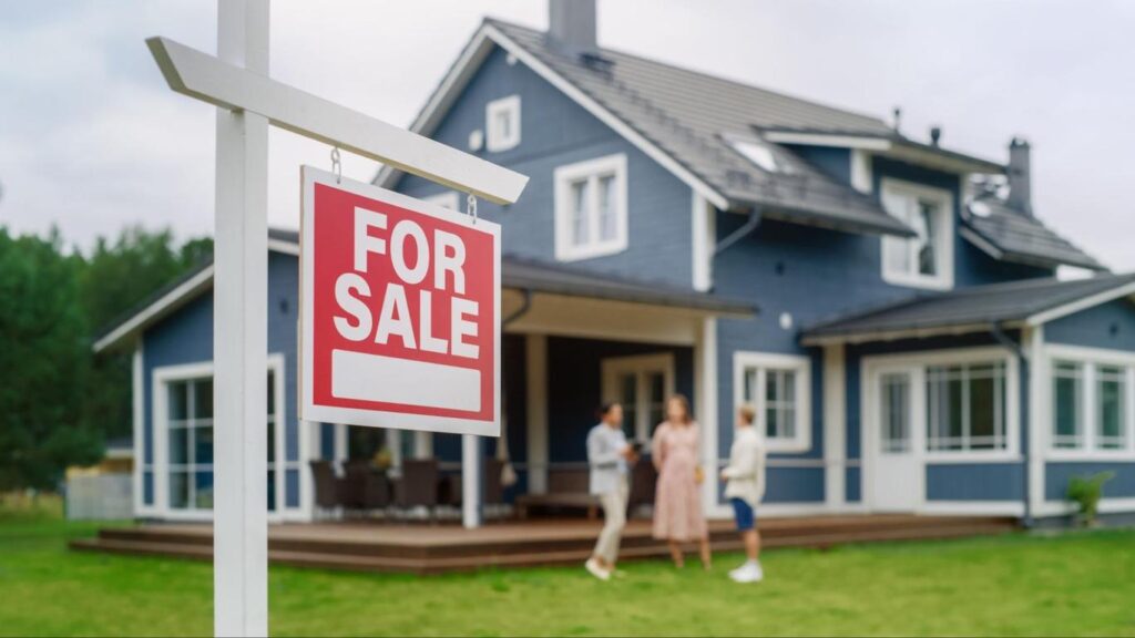 For sale sign in front of blue house