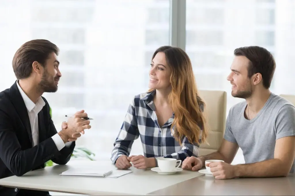 Couple talking to a man at a conference table.