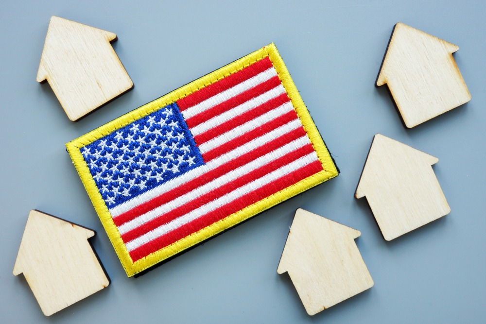 An American flag patch is surrounded by small wooden cutouts in the shape of houses. 