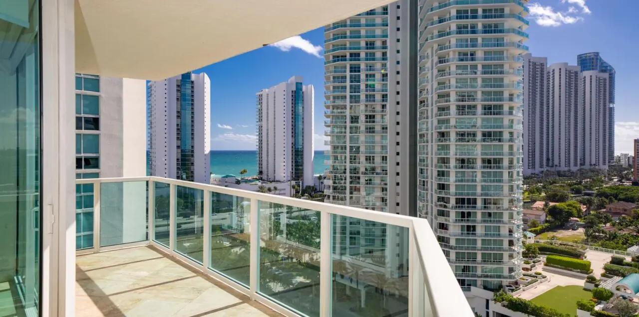 A view of buildings near the water on a sunny day as seen from the balcony of a condo.