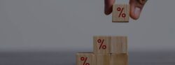 A hand stacking wooden blocks with a red % sign drawn on them.