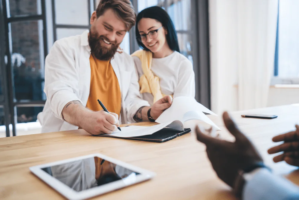A young happy couple signs a mortgage document.