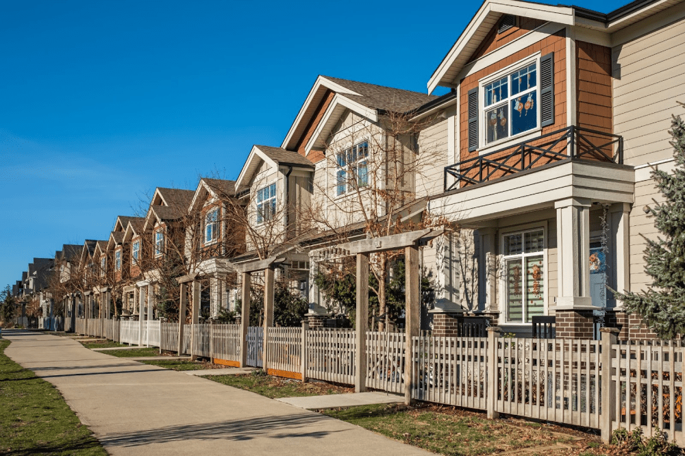 A row of modern townhouses along a street in a suburban neighborhood. 