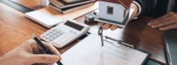 A mortgage broker passes a model home to a person signing a contract.