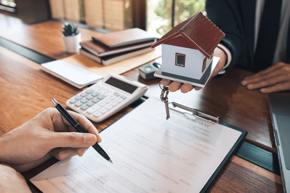 A mortgage broker passes a model home to a person signing a contract.
