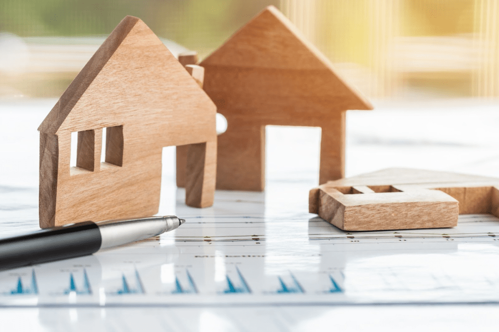 Wooden model homes on top of financial analysis documents. 