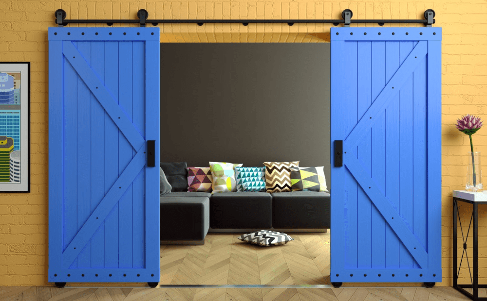 Blue barn doors open to reveal a couch with colorful pillows on it.