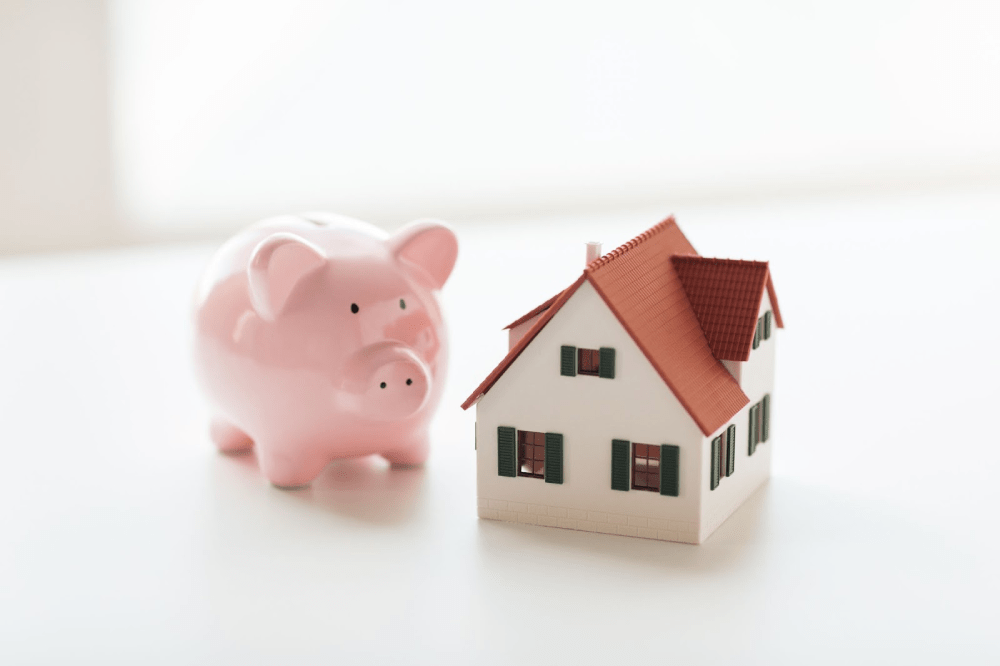 A model home next to a piggy bank.