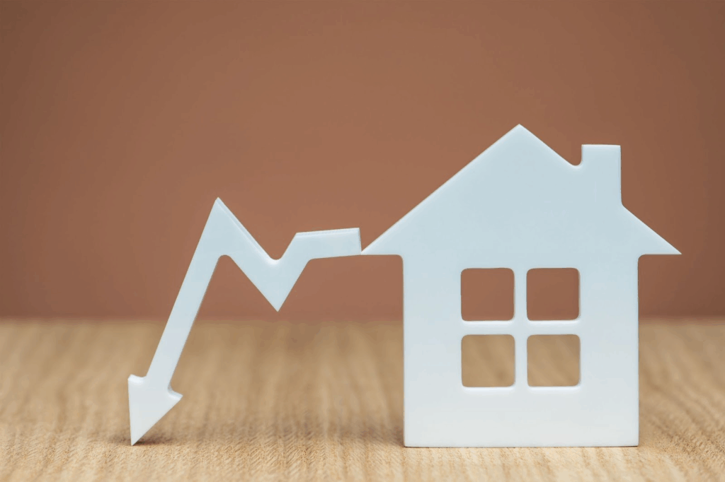 A white outline of a home with an arrow plunging downward next to it.