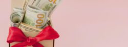 Cash stuffed inside a box with a red bow tied around it.