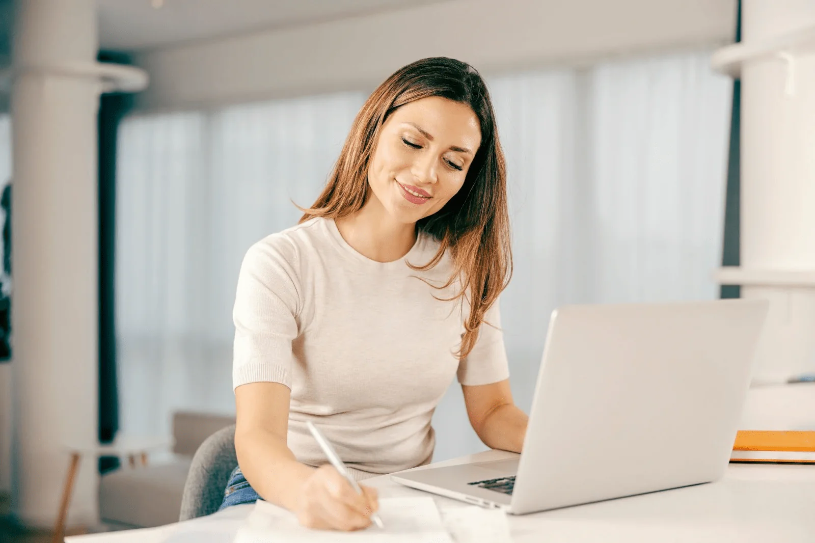 A smiling young woman sitting at her laptop does her taxes
