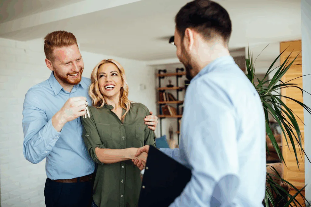 A couple shaking hands with their realtor and receiving the keys to their new home.
