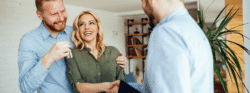 A couple shaking hands with their realtor and receiving the keys to their new home.