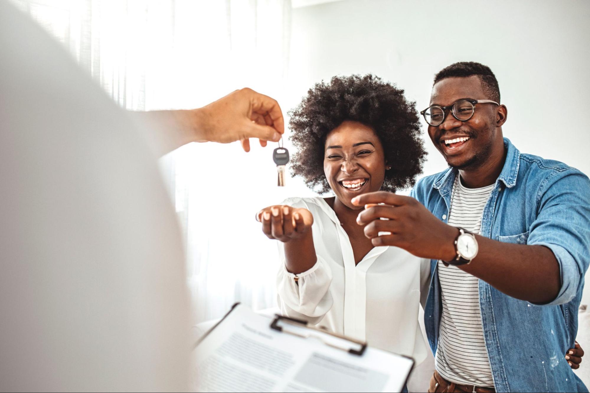 A young black couple getting handed the keys to their new home.