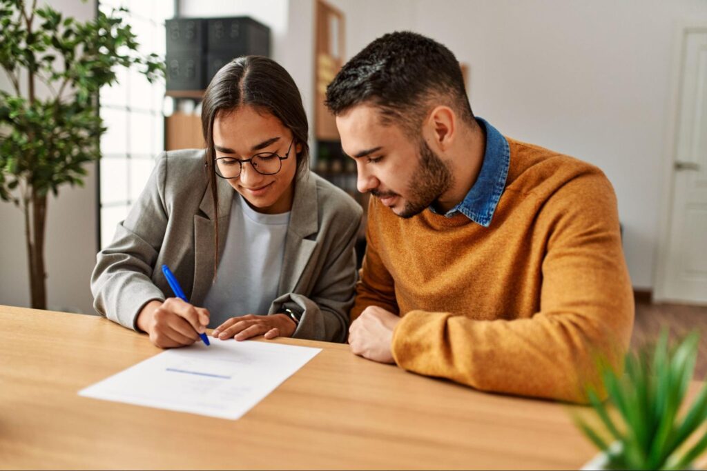 A young couple signs a mortgage document.