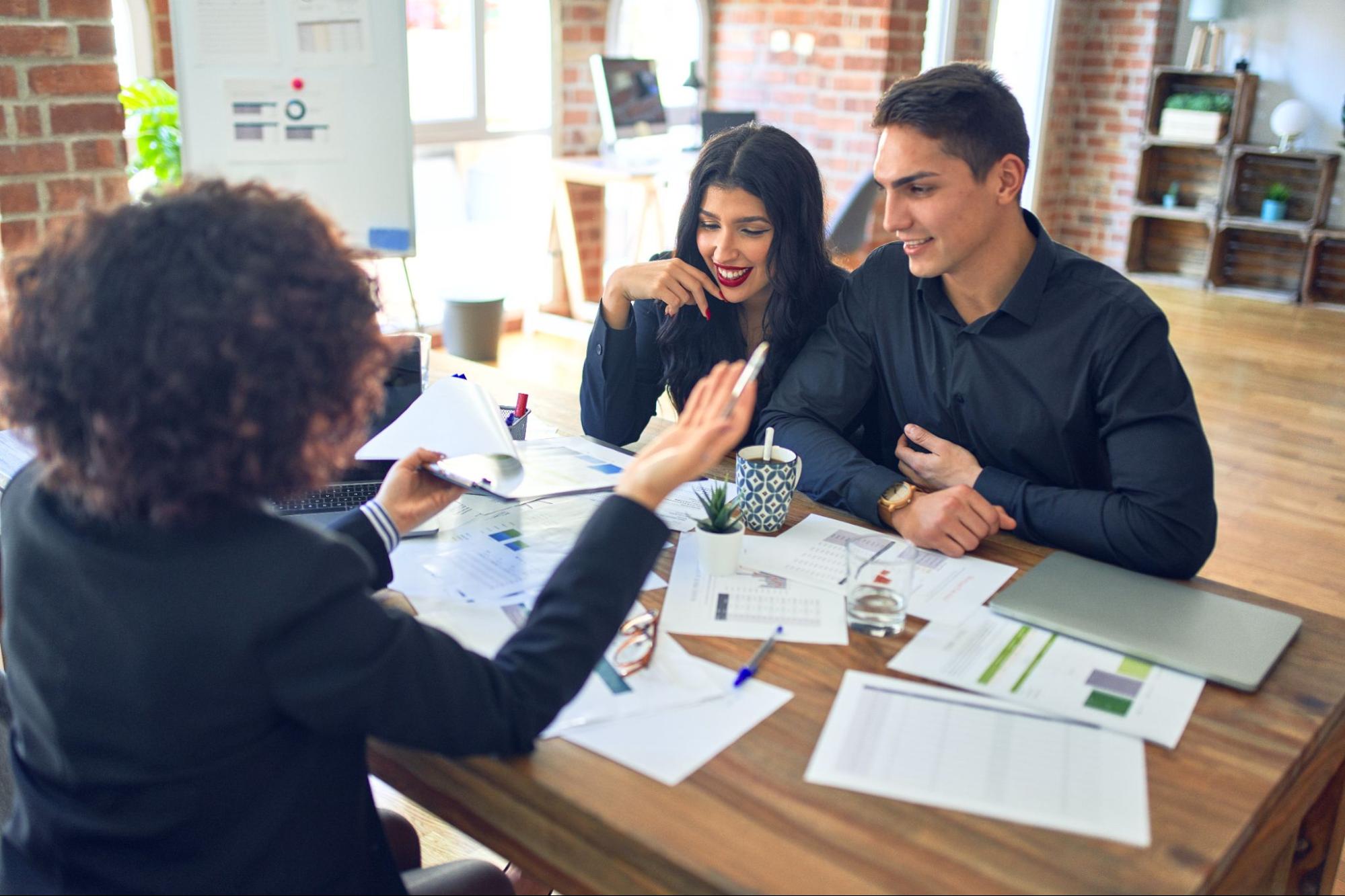 A couple speaks with their mortgage lender in her office.