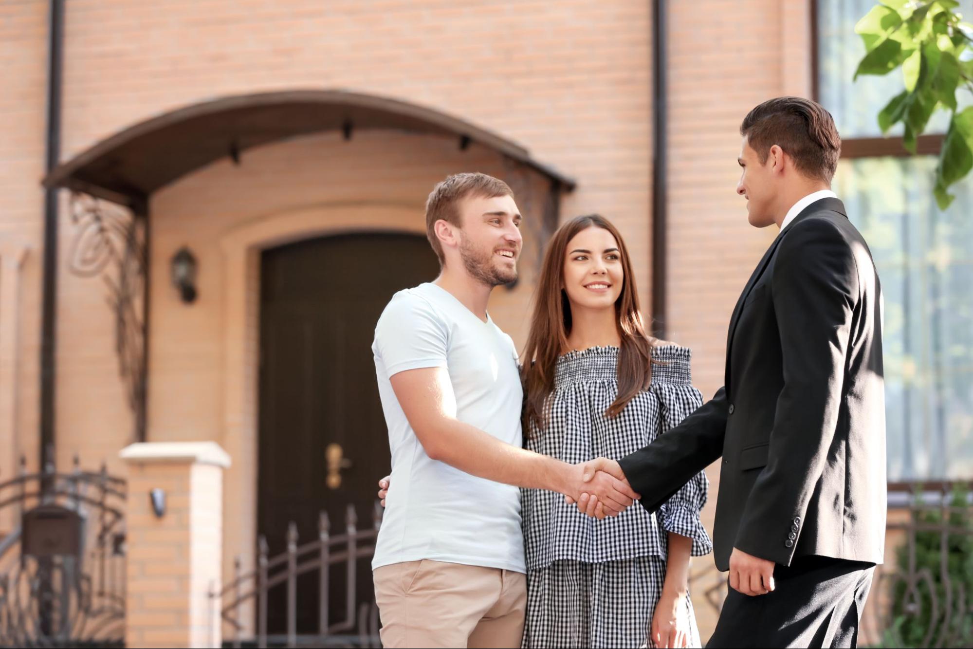 A young couple shakes hands with their realtor. 