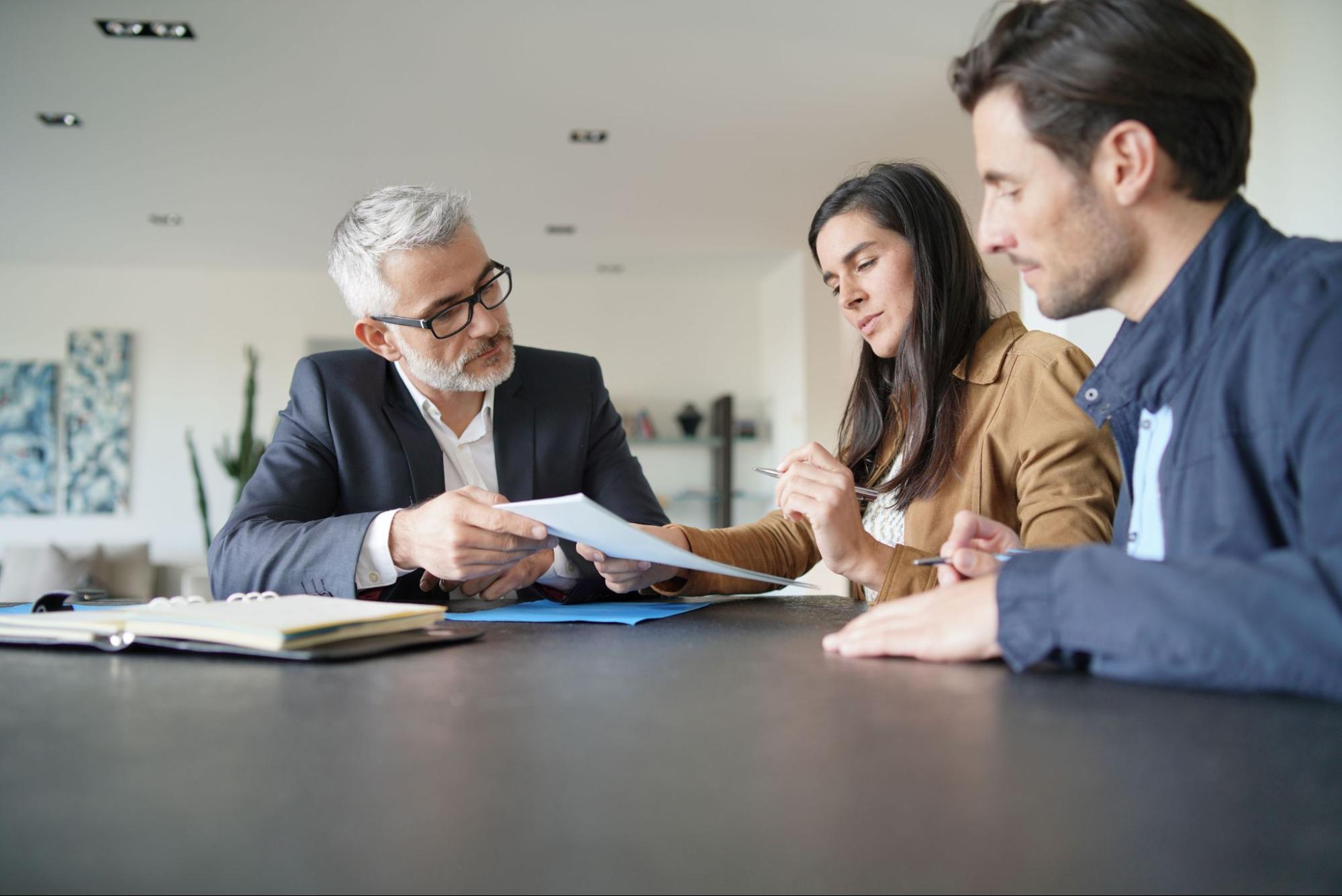 A young couple reviews their mortgage contract with their lender. 