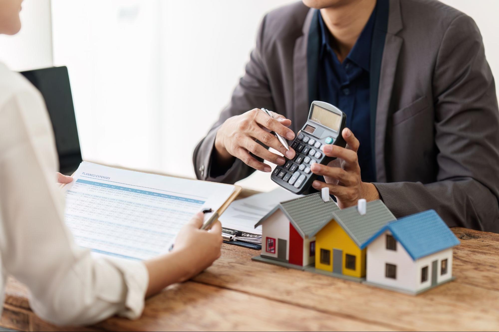 A borrower and lender calculating home appreciation at an office desk.