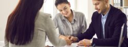 A couple signing documents with a mortgage professional.