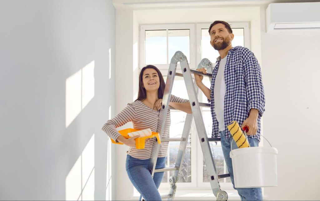 A young couple with paint buckets doing home maintenance.