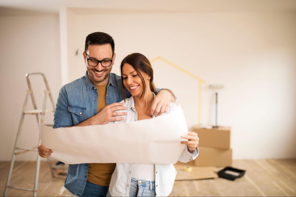 Smiling couple reviewing renovation blueprint.