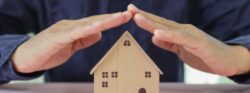 image1 A person holding their hands over the roof of a model home.