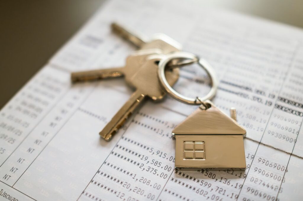 House keys and home-shaped keychain resting on financial documents