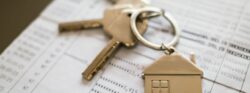 House keys and home-shaped keychain resting on financial documents