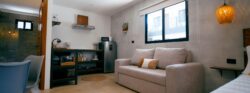 image2 Modern vacation rental studio with a sofa, kitchenette, dining area, and large window.