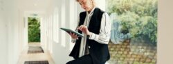 Older businesswoman using a tablet while sitting beside a large window in a bright modern office.