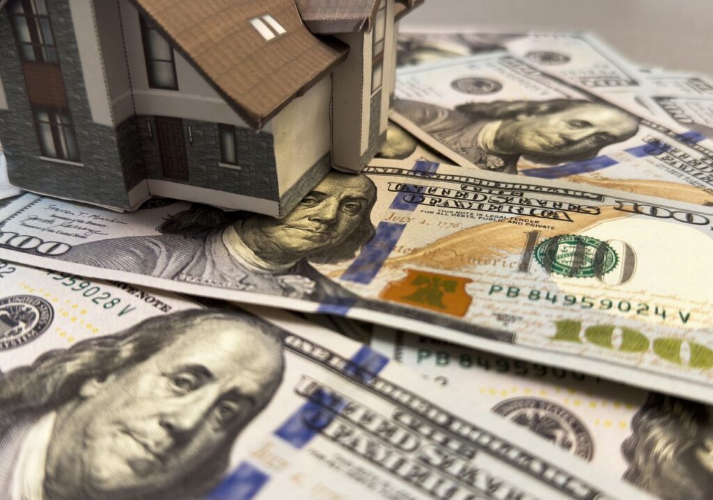 Model house sitting on U.S. dollar bills representing real estate financing and mortgage investment