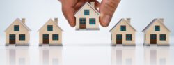 Person's,Hand,Choosing,A,House,Model,From,The,Row,Over Person's,Hand,Choosing,A,House,Model,From,The,Row,Over